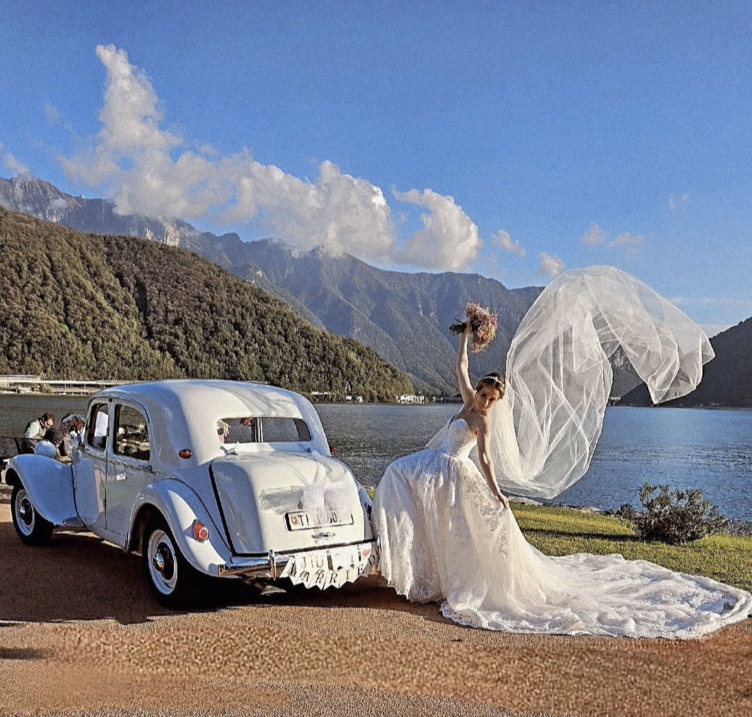 La sposa alza il bouquet, il velo al vento sul lago